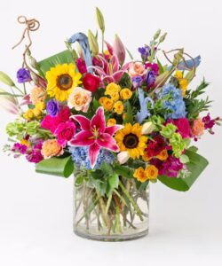 Romantic flower arrangement with sunflowers, ranunculus and pink lilies, available for same-day delivery in Georgetown, TX.